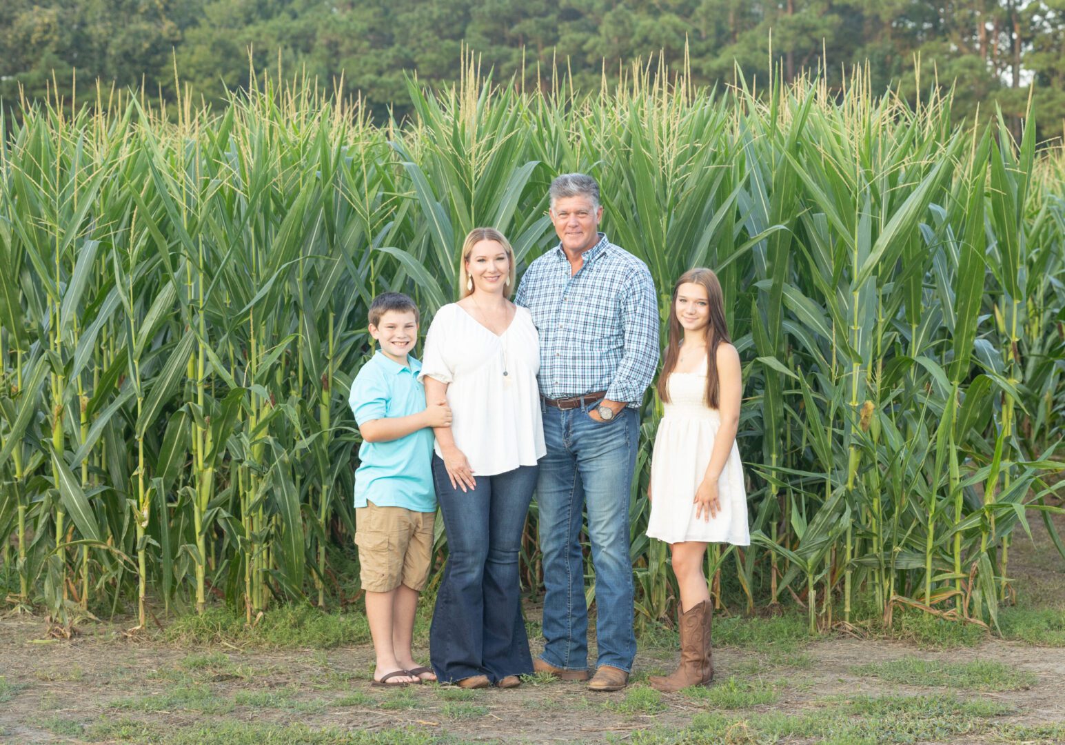 A family standing in front of a corn field.